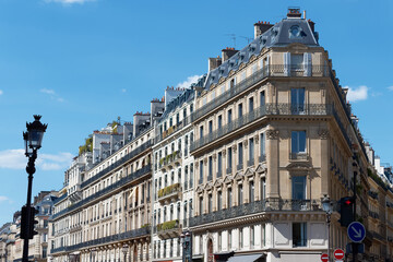 Magnificent Haussmann-style apartment buildings line the Avenue de l'Opera in the 2nd district of Paris, under a vivid blue sky. © kovalenkovpetr