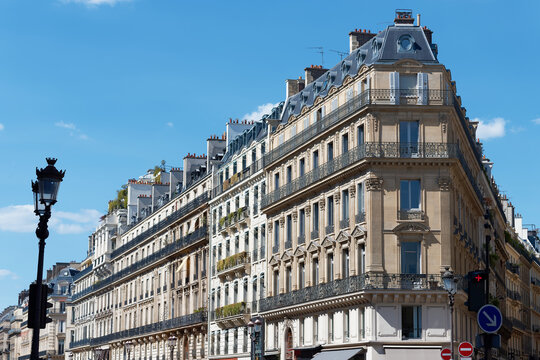 Magnificent Haussmann-style apartment buildings line the Avenue de l'Opera in the 2nd district of Paris, under a vivid blue sky.
