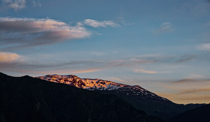 Obraz premium Golden Hour Glow on Snowy Mountain Peaks with Serene Sunset Sky