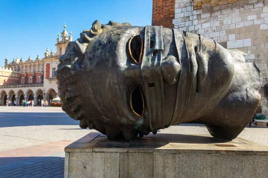 The famous giant bronze head sculpture Eros Bendato by Igor Mitoraj on the Main Market Square near the Town Hall Tower in Krakow, Poland