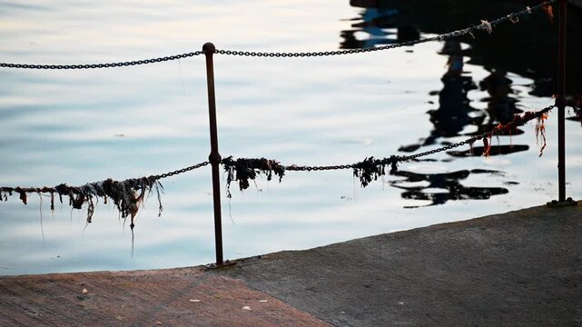 Rusty harbour chain with gentle water reflections at sunset