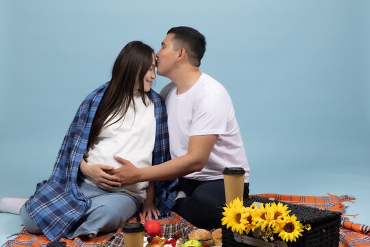 Happy romantic couple sitting close together on blanket enjoying picnic