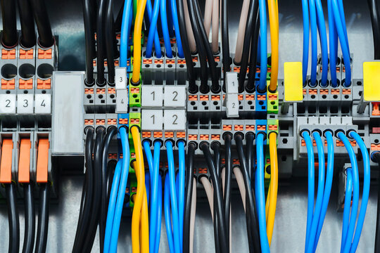 Rows of electrical relays and circuit breakers line the scene. Wires connect to each device in neat arrangements. This industrial setup features a clean, organized layout
