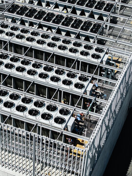 Aerial view of industrial HVAC cooling units with rows of large fans and metal framework on a rooftop in Riga, Latvia.