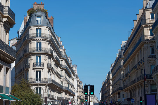 Perfectly symmetrical Parisian streetscape along the Rue du Quatre-Septembre, with elegant Haussmann apartment buildings lining both sides under a flawless cobalt blue sky.