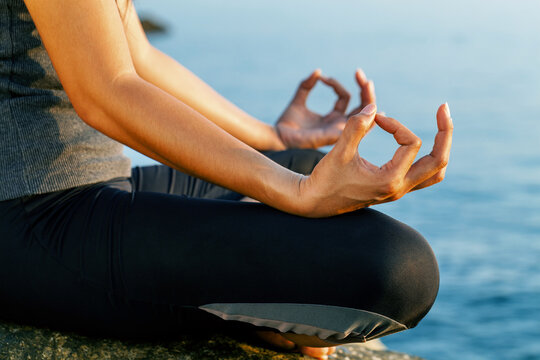 close-up woman meditating in yoga pose the sea