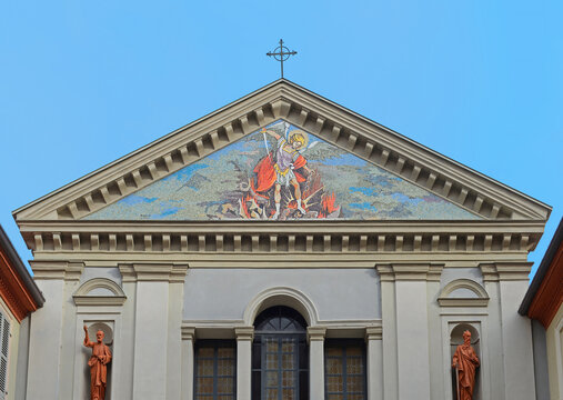 Top gable of Saint Michaels church (San Michele Arcangelo) with colourful mosaic of the archangel beating the dragon or devil in Tortona, Italy with blue sky