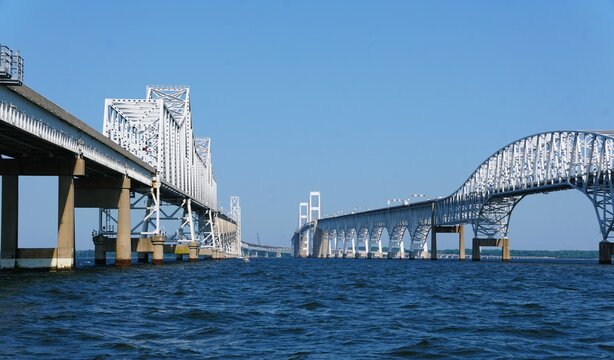 The view of Chesapeake Bay Bridge with distinct truss span across calm bay under a clear blue sky near Annapolis, Maryland, U.S.A