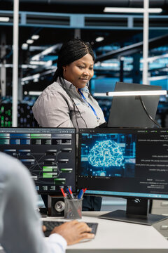 Data center IT administrator applying AI to reduce downtime. African American staff member designs and implements AI driven solutions for server facility equipment.