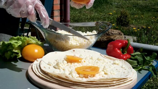 the process of cooking pita bread with cheese yellow tomatoes in sunlight cooking pita bread for lunch. High quality 4k footage