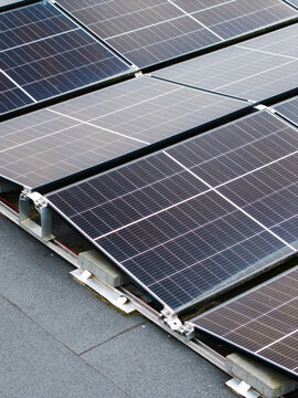 Aerial view of solar panels installed on a flat roof with mounting brackets and concrete blocks in Malpils, Sigulda Municipality, Latvia.