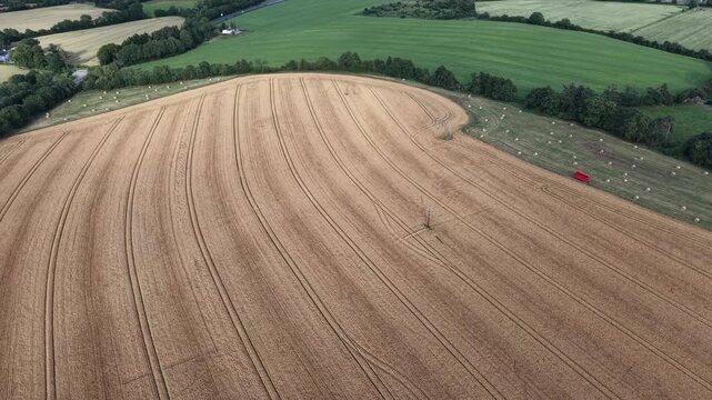4K Aerial View of Harvested Farmland With Crop Rows and Green Fields