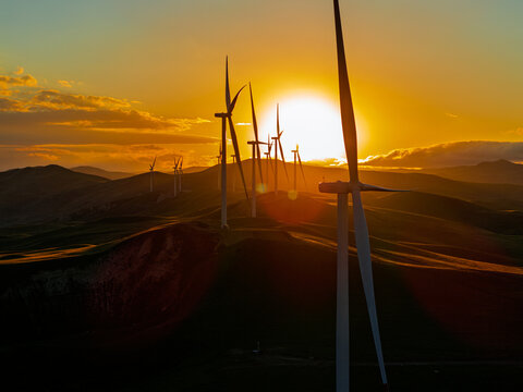 Beautiful sunset field with wind mill generators. Windmill silhouette on mountain at sunset