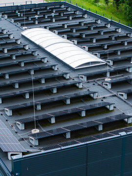 Aerial view of a flat building roof featuring rows of solar panels and a central arched skylight in Ikskile, Ogre Municipality, Latvia.