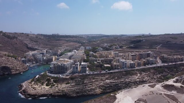 Aerial view of Xlendi Bay featuring the historic watchtower on the rocky cliffs and coastal buildings in Munxar, Gozo Region, Malta. High quality 4k footage