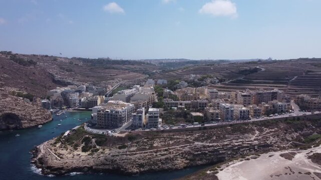 Aerial view of Xlendi Bay featuring the historic watchtower on the rocky cliffs and coastal buildings in Munxar, Gozo Region, Malta. High quality 4k footage