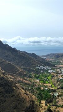 Beautiful panoramic perspective of the verdant Agaete Valley in Gran Canaria, featuring a small village nestled among mountains and the Atlantic Ocean