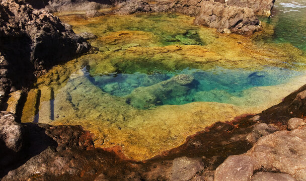 Gran Canaria, calm rock pools under steep cliffs of the north coast are separated from the ocean by volcanic rocks of platform constructed by old lava flowsPunta de Galdar area