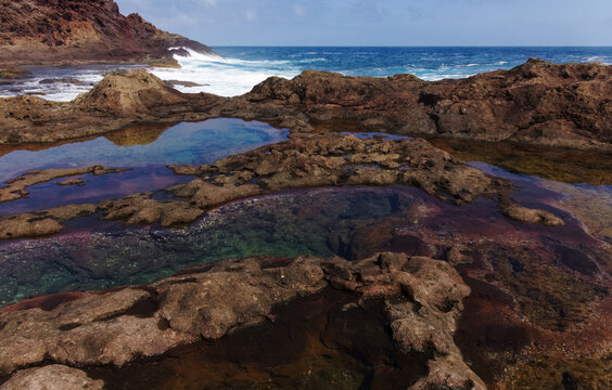 Gran Canaria, calm rock pools under steep cliffs of the north coast are separated from the ocean by volcanic rocks of platform constructed by old lava flowsPunta de Galdar area