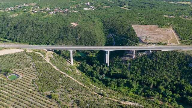 Aerial drone view of modern highway viaduct stretching across a green mountain landscape