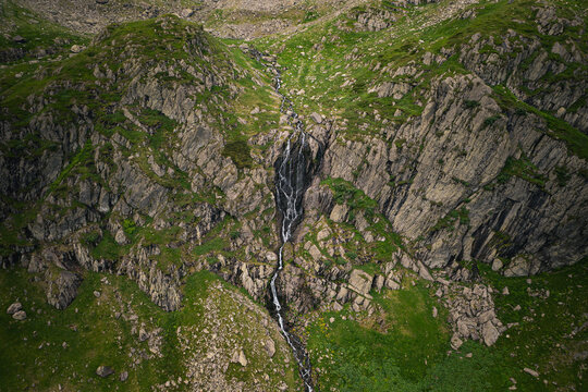 Aerial view of a cascading waterfall flowing down the rocky slopes of Negoiu Peak in the Fagaras Mountains near Porumbacu de Jos, Sibiu, Romania.