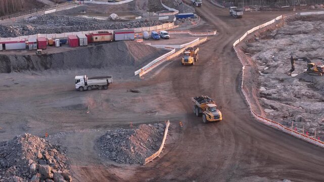 Espoo, Finland-April 14, 2025: Yellow dump trucks transport crushed stones within a quarry in Finland, showcasing the process of aggregate production for construction purposes
