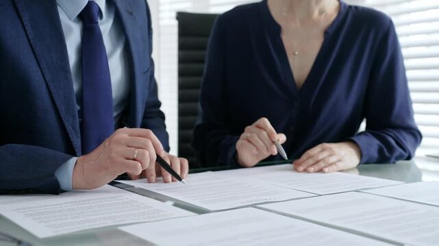 Business people hands discussing contract terms and analyzing paperwork, reviewing legal documents during a corporate meeting in a modern office, planning strategy