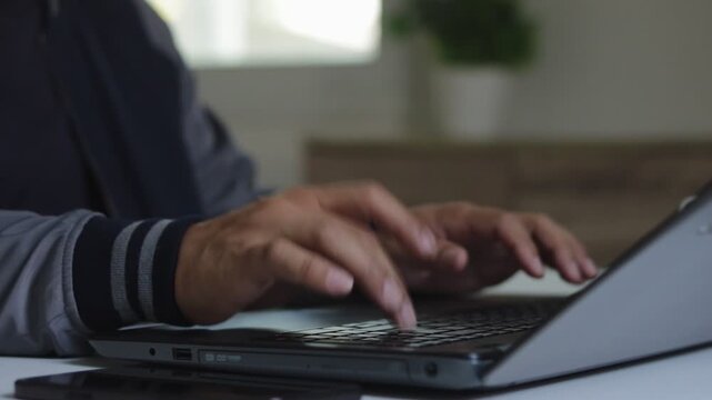 Closeup of man hand using smartphone and typing on laptop keyboard in modern workspace, multitasking, digital communication, remote work, mobile technology, cybersecurity, online business productivity