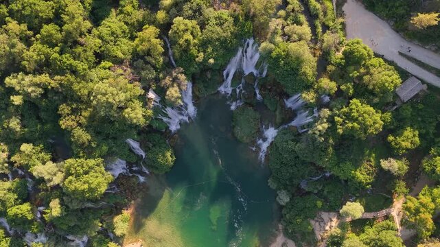 Top down aerial view of emerald river flowing through lush forest with dramatic cliffs