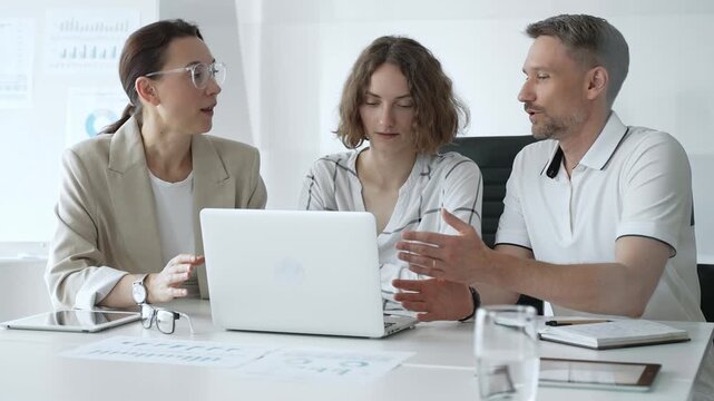 Business professionals reviewing marketing analytics on laptops, working together strategically in contemporary workplace with minimalist interior design and collaborative atmosphere