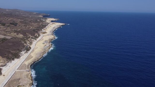 Xwejni s centuries-old salt pans unfold along the rugged coast of Zebbug, Gozo, geometric pools and vivid Mediterranean blues in a sweeping summer Aerial view. High quality 4k footage