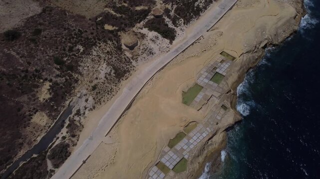 Xwejni s centuries-old salt pans unfold along the rugged coast of Zebbug, Gozo, geometric pools and vivid Mediterranean blues in a sweeping summer Aerial view. High quality 4k footage