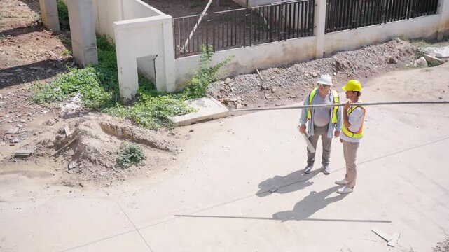 Construction site foreman worker and supervisor engineer inspecting exterior building structure for residential housing project construction management site supervision and real estate development