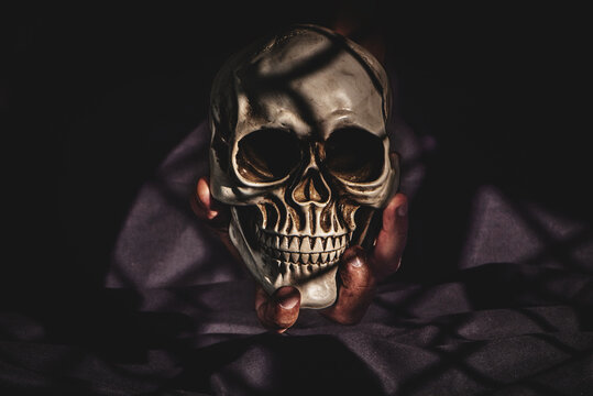 Concept of memento mori with a human hand holding a skull.