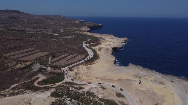 Xwejni s centuries-old salt pans unfold along the rugged coast of Zebbug, Gozo, geometric pools and vivid Mediterranean blues in a sweeping summer Aerial view. High quality 4k footage