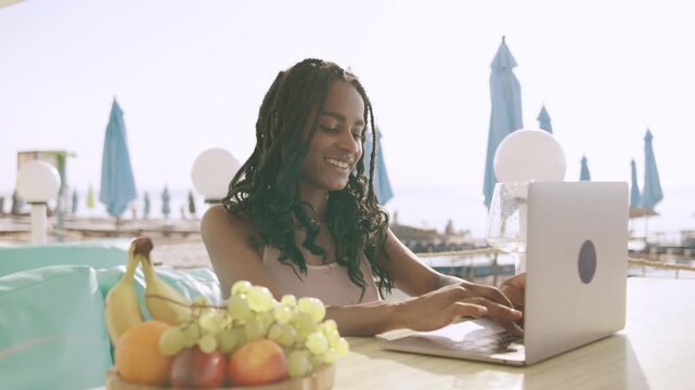Summer fun at the beach with friends enjoying a picnic and working on a laptop by the sea during a sunny Caribbean holiday