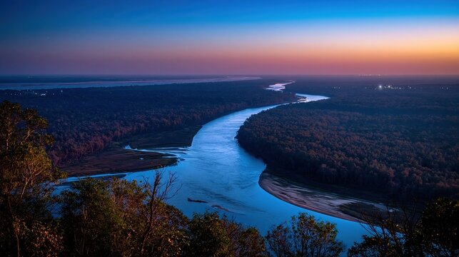Aerial view of a winding river delta at blue hour with a dense forest canopy and glowing lights for travel and nature background