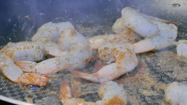 Close up macro view of raw prawns cooking over a hot stove burner