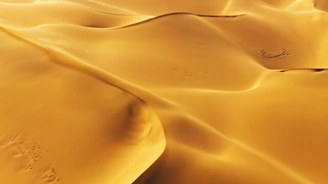 Aerial view of golden sand dunes in desert showing wind-swept patterns and textures.
