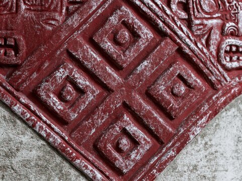 Red tribal cultural art sculpture featuring intricate geometric symbols and mask motifs for archaeological display, ethnic museum exhibition and cultural advertising
