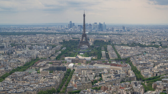 Aerial view of the Eiffel Tower rising above the dense urban landscape, with the skyscrapers of La Defense in the distance Paris, Ile-de-France, France.