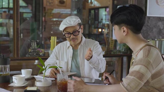 Small business, mentorship, coaching, cafe owner, discussion with positive emotion between senior and young worker, reflecting successful knowledge transfer and family business bonding father and son