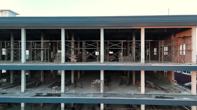 An unfinished commercial concrete building, currently under construction, equipped with scaffolding and unfinished floors.