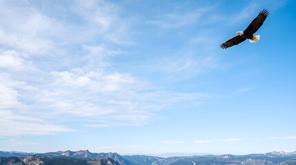 Fototapeta premium Bald eagle soaring over a mountainous landscape with a blue sky