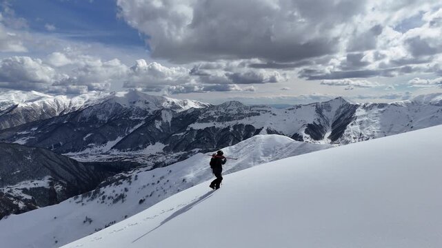 Aerial drone view of a skier hiking up a peak in Gudauri, Georgia. Cinematic minimalist shot of winter mountain freeride filled with zen tranquility.