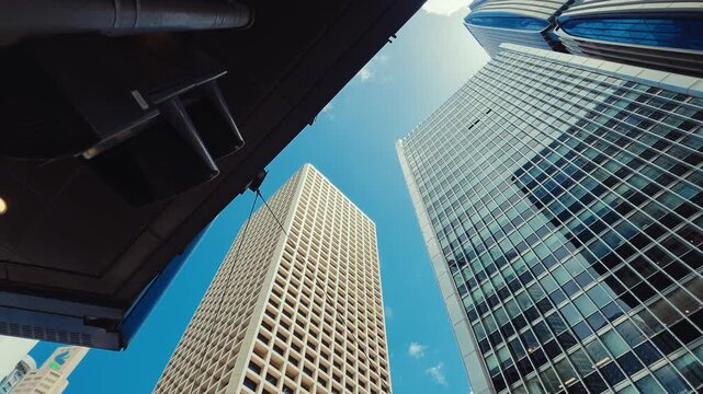 A low-angle shot captures towering modern skyscrapers in Hong Kong against a clear blue sky