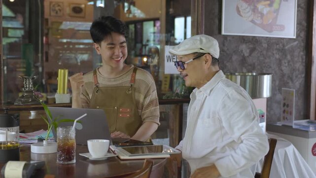 Modern small business digital technology, father and son cafe owner, young entrepreneur management, using laptop and tablet planning orders finance workflow efficiency technology business operation