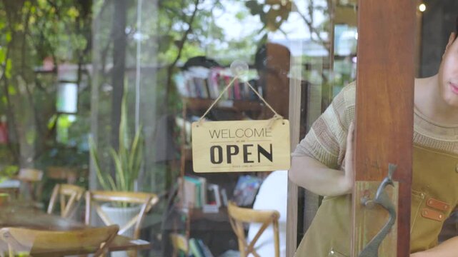 Cafe owner adjusting closed sign while looking through glass window, small business routine showing responsibility and daily management, lifestyle of entrepreneur balancing service and rest time.