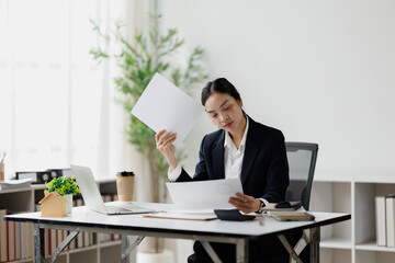 Fototapeta premium Asian businesswoman feeling overwhelmed by office paperwork