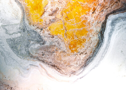 Aerial view of the mineral-rich salt flats of Owens Lake with vibrant orange and white crust patterns in Inyo County, California, United States.